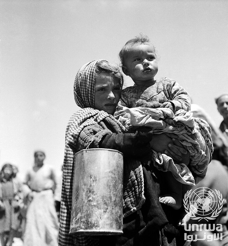 Palestinian refugee girl carrying her baby brother while waiting for UNICEF rations in 1948–49